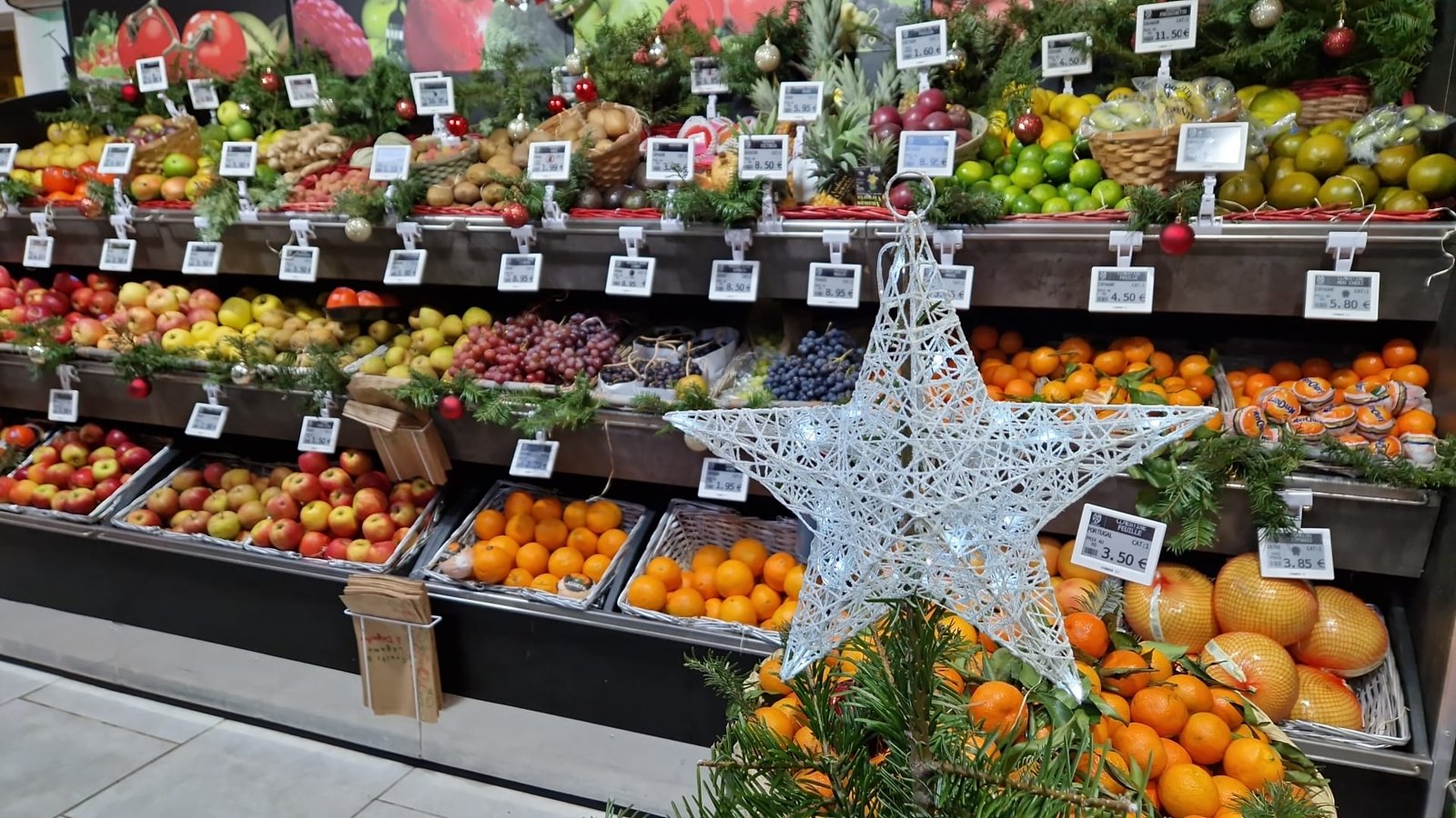 Color and monochrome electronic shelf labels across a fresh-produce display in a supermarket