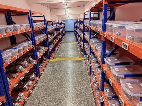 Warehouse shelving with e-ink bin labels identifying parts inventory